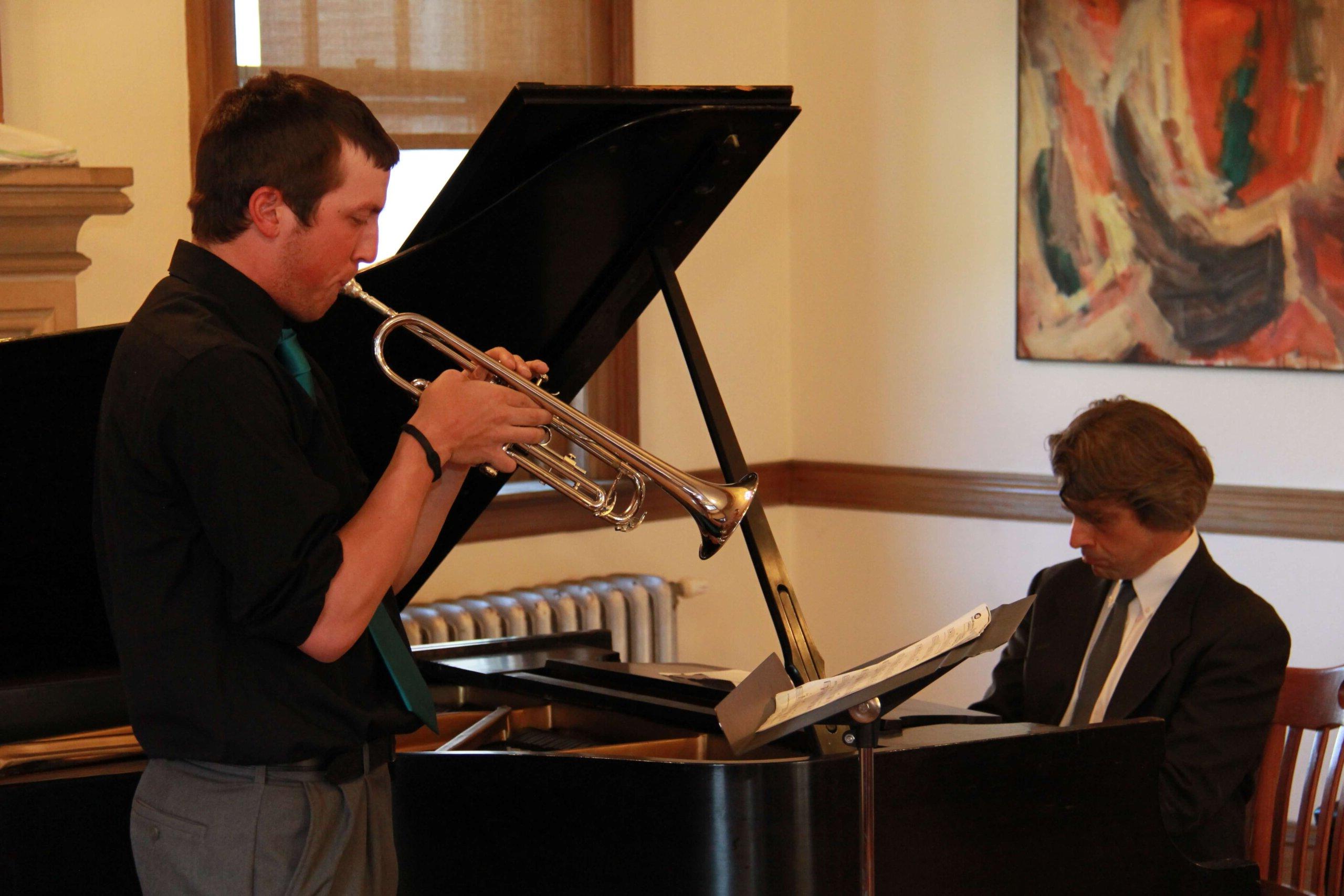 Chris Bakriges教授弹钢琴和一个学生吹小号的照片