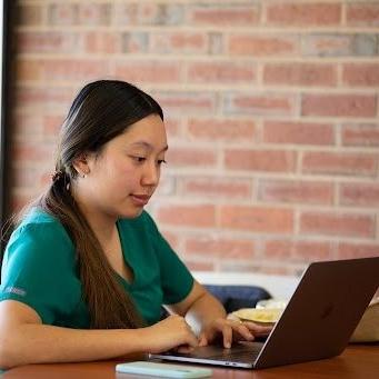 Photo of a nursing student, studying on a laptop in the library